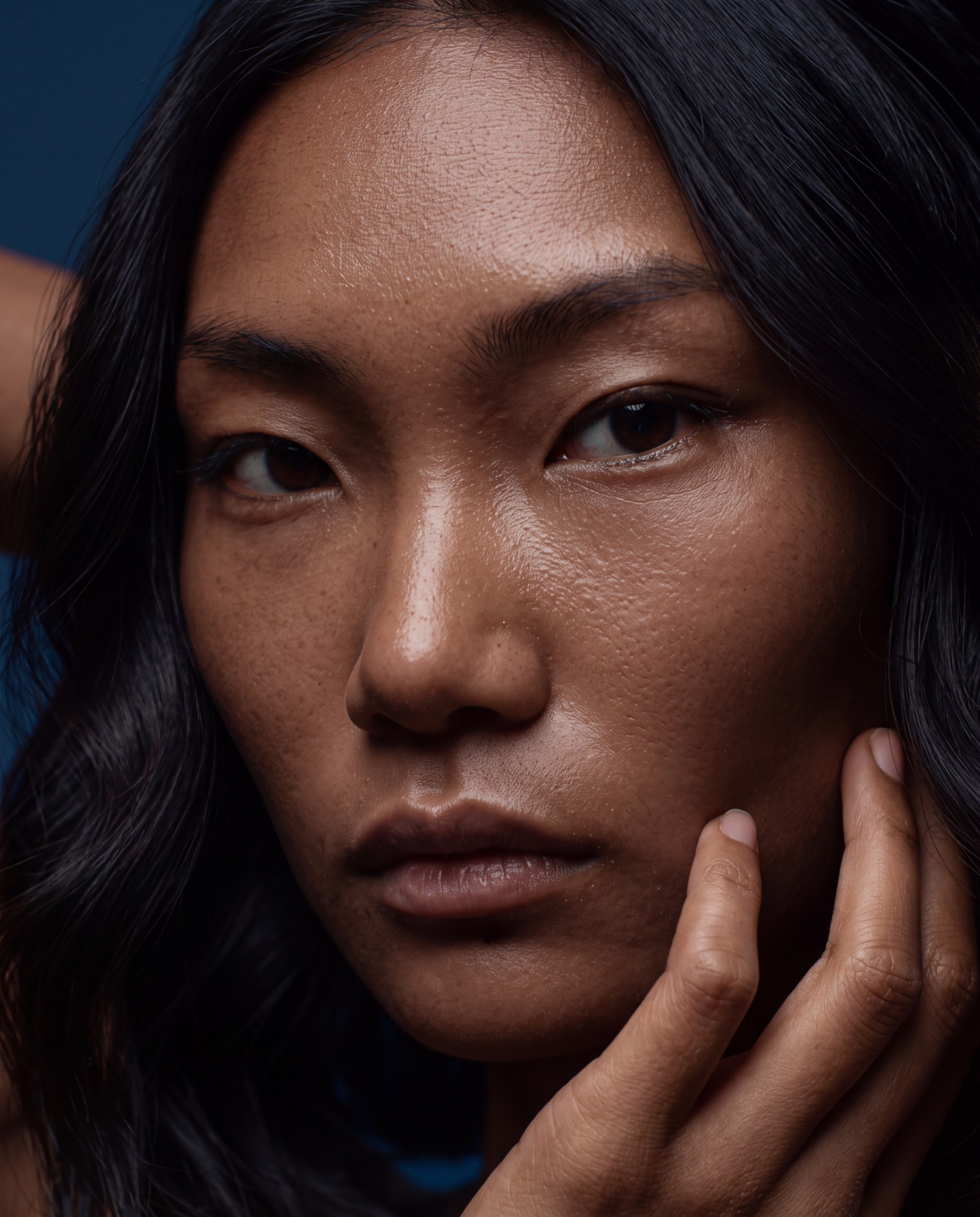 Close-up portrait of a woman with her hand resting against her cheek